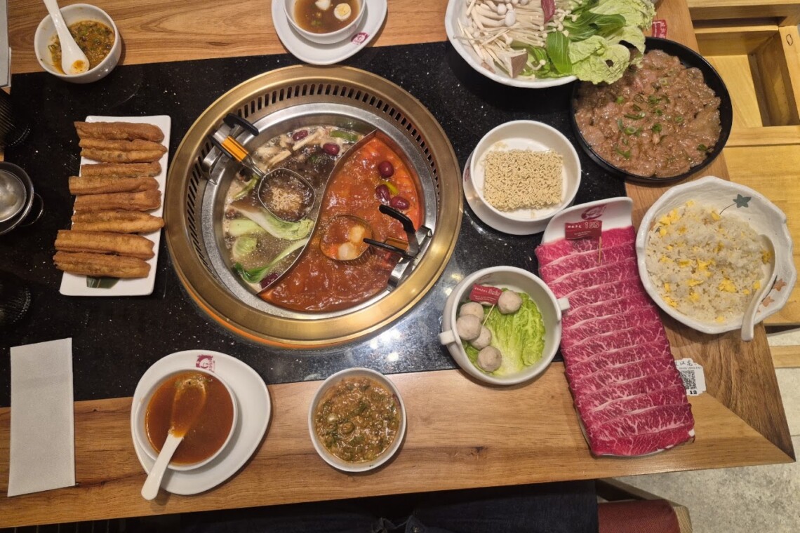 Hot pot table at Borsay Torrevieja with divided broth, sliced beef, mushrooms and dipping sauces