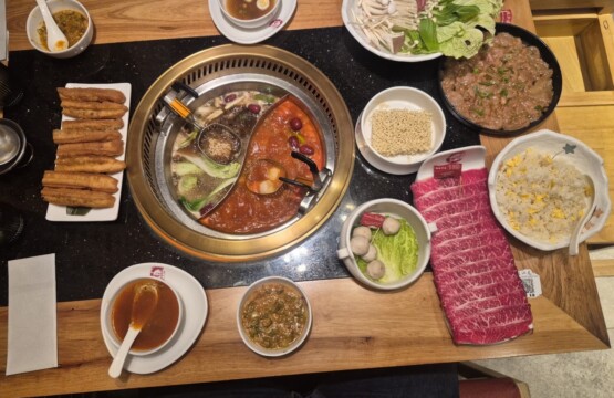 Hot pot table at Borsay Torrevieja with divided broth, sliced beef, mushrooms and dipping sauces