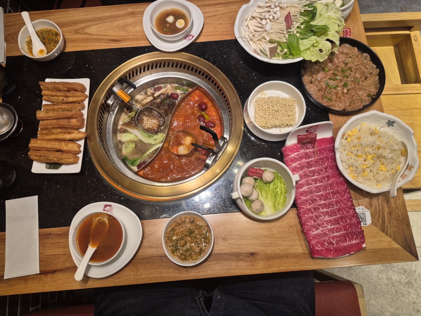 Hot pot table at Borsay Torrevieja with divided broth, sliced beef, mushrooms and dipping sauces