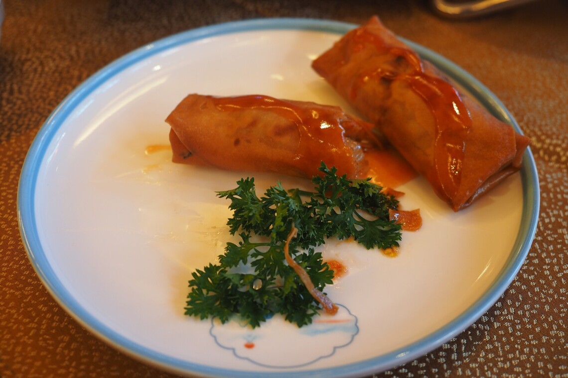 Crispy Chinese spring rolls with sweet and sour sauce on a restaurant plate