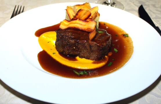 Grilled fillet steak served with sauce and vegetable garnish on a white plate