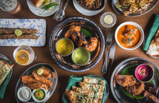 Indian restaurant table spread with tandoori chicken, kebabs, naan bread and curries