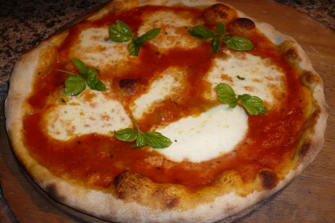 Wood-fired margherita pizza with mozzarella and fresh basil on a wooden board