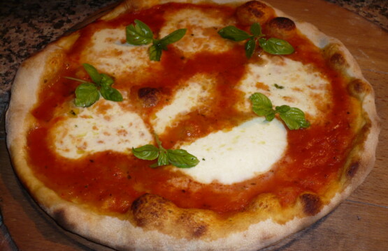 Wood-fired margherita pizza with mozzarella and fresh basil on a wooden board