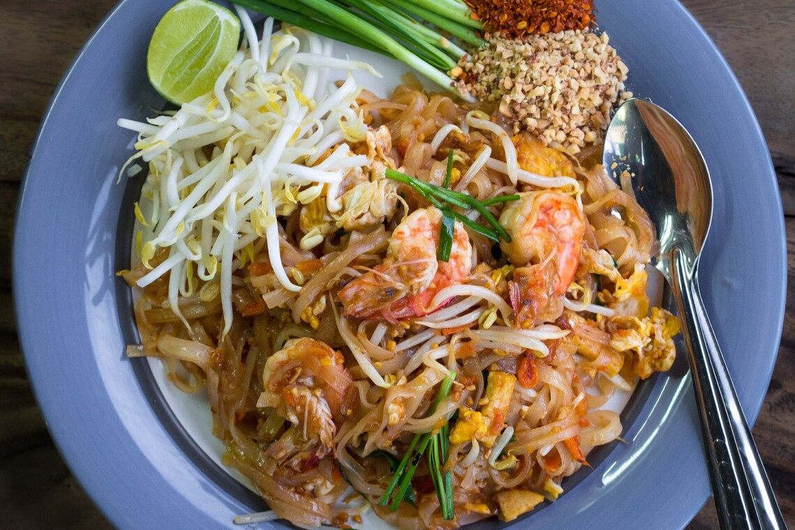 Pad thai with prawns, bean sprouts, lime and crushed peanuts on a restaurant plate